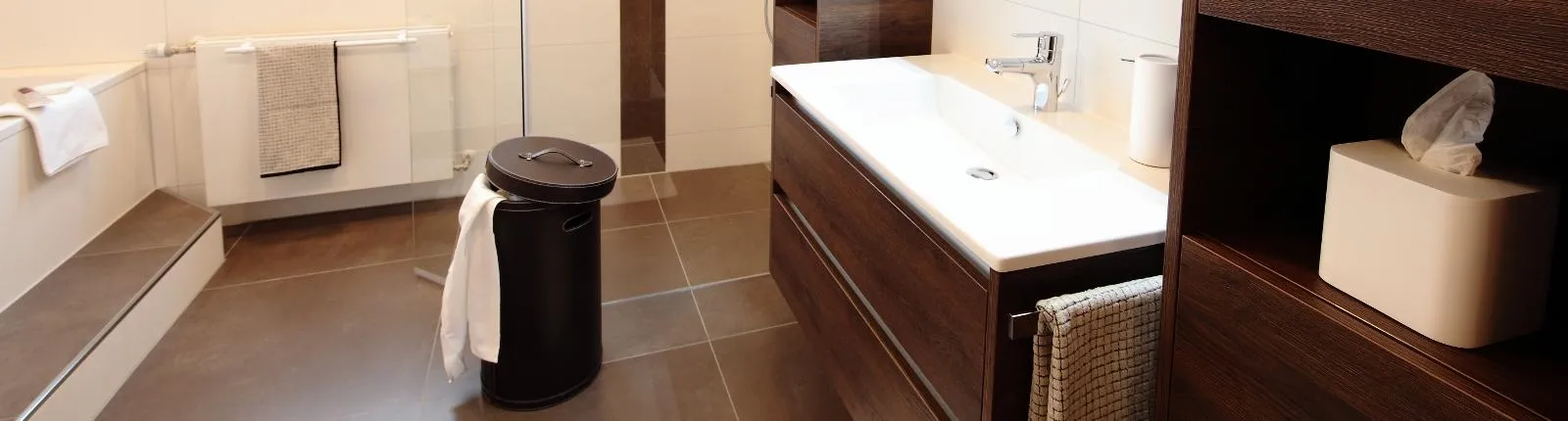 Modernes Bad mit großer Dusche, Holz-Waschtisch, Handtüchern und stilvollen Bad-Accessoires