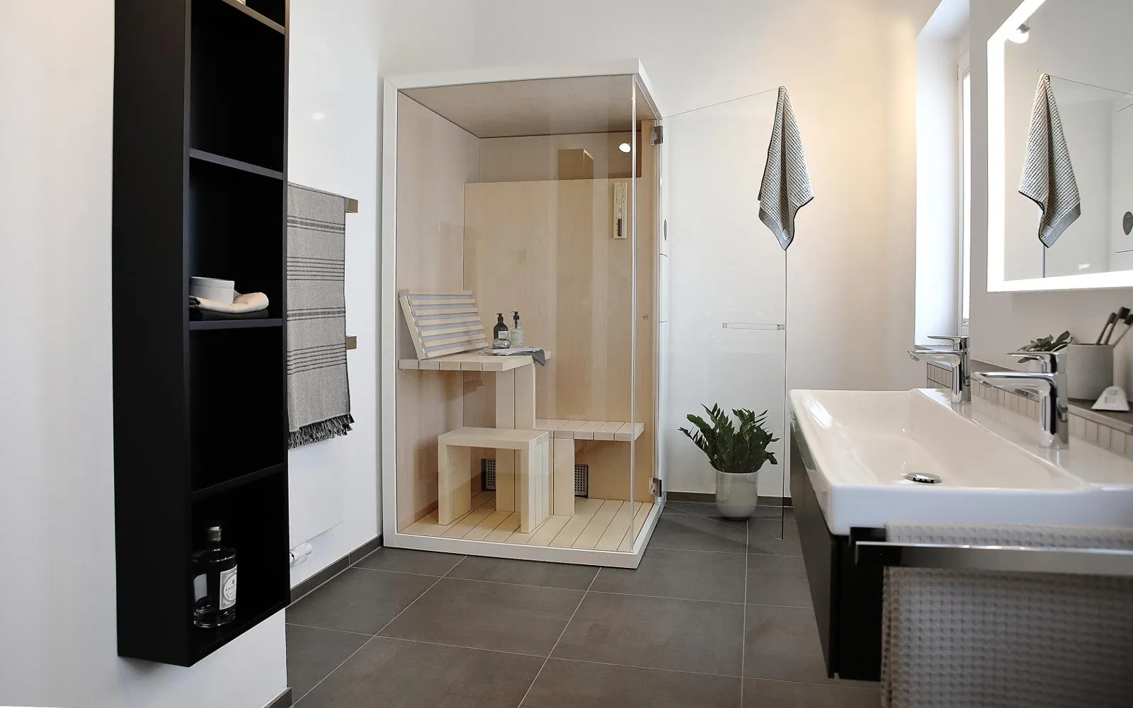 Modernes Wellnessbad mit kompakter Sauna, Doppelwaschtisch, großem Spiegel und stilvollen Details.
