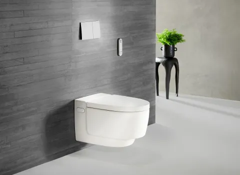 Dusch-WC AquaClean Mera Comfort mit weißer Abdeckung vor dunklen Wandfliesen.