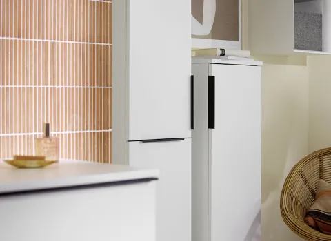 Ein Blick auf zwei hohe, weiße Schränke der Burgbad Eqio-Kollektion, die im Badezimmer nebeneinander platziert sind und sich durch ihre schlichte Ästhetik und schwarzen Griffe auszeichnen.