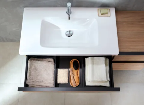 Eine Vogelperspektive auf ein modernes Waschbecken mit einem geöffneten Schubfach darunter.