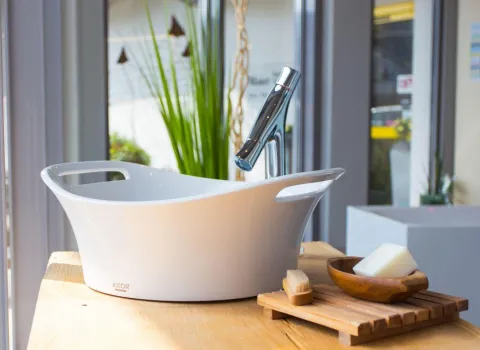 Modernes Waschbecken mit Design-Armatur, Seifenschale und Accessoires in einer hellen Badausstellung.