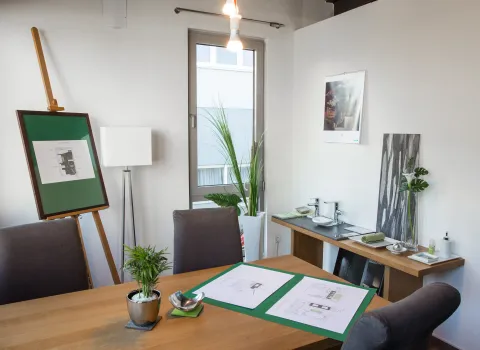 Moderner Beratungsraum mit Tisch, Bauplänen und Mustern für Badgestaltung bei bad & heizung Maier.