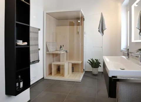 Modernes Wellnessbad mit kompakter Sauna, Doppelwaschtisch, großem Spiegel und stilvollen Details.