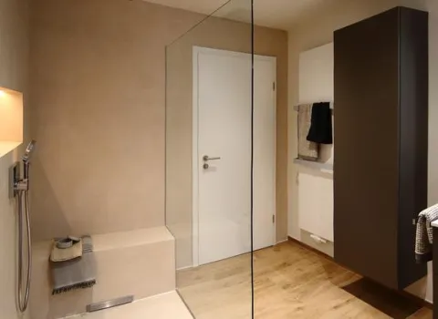 Helles Wohnbad mit begehbarer Dusche, Sitzbank, Handbrause sowie modernem Schrank und Holzboden.