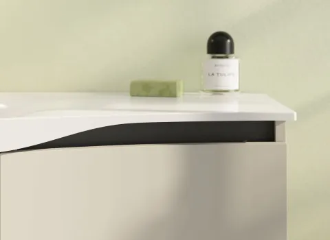 Das Bild zeigt ein elegantes Waschtischdetail mit einer geschwungenen, weißen Waschtischplatte und sanft gerundeter Front in hellem Beige.