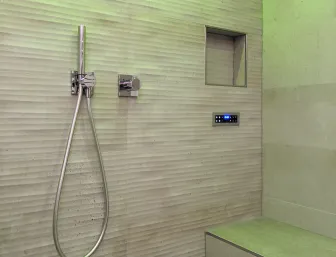 Eine moderne Dusche mit strukturierten, beigen Fliesenwänden, die eine elegante Rillenoptik aufweisen.