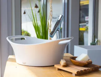 Modernes Waschbecken mit Design-Armatur, Seifenschale und Accessoires in einer hellen Badausstellung.