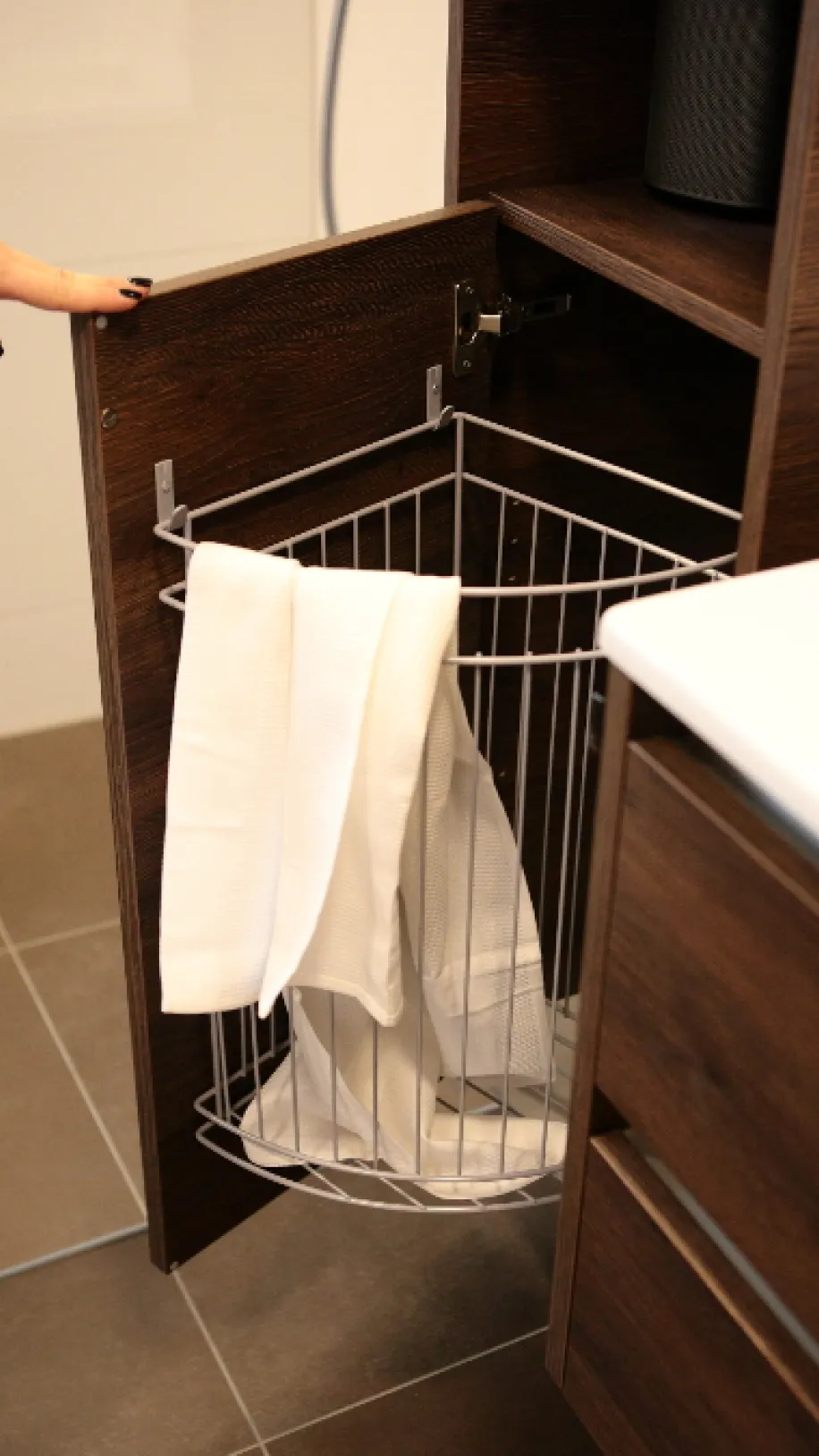 Praktischer ausziehbarer Wäschekorb im Badmöbel mit Handtüchern.