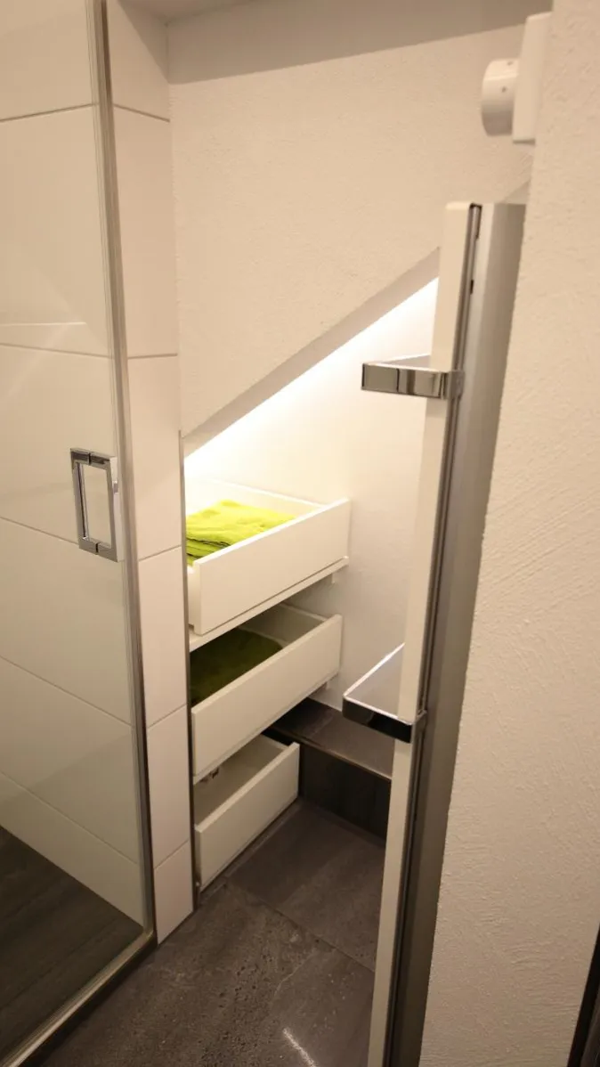 Maßgefertigte Einbauschränke mit Schubladen unter der Dachschräge im modernen Badezimmer.