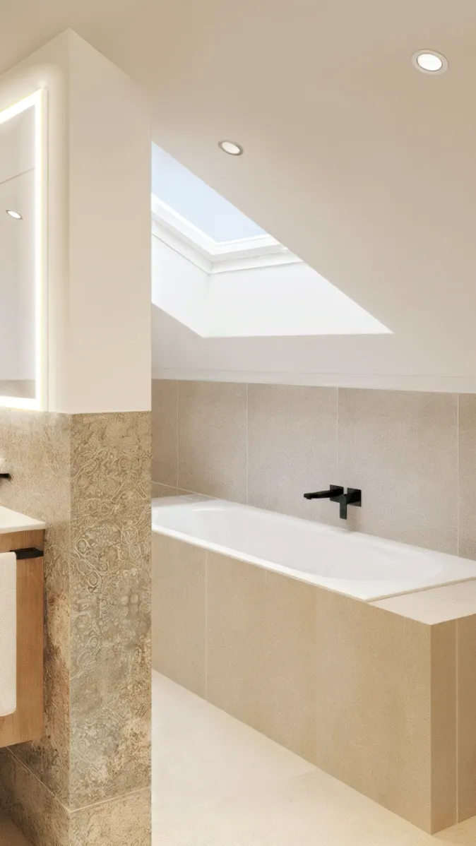 Ein modernes Badezimmer im Dachgeschoss mit einer eingebauten Badewanne unter einem großen Dachfenster. Die hellen Fliesen und das natürliche Licht schaffen eine ruhige Atmosphäre. Schwarze Armaturen setzen elegante Kontraste. Der Raum wirkt klar und harmonisch.