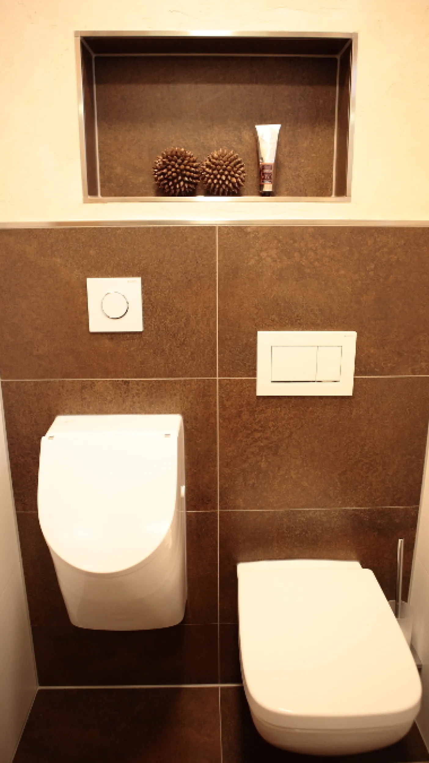 Gäste-WC mit Wand-WC, Urinal und Nische mit dekorativen Accessoires.