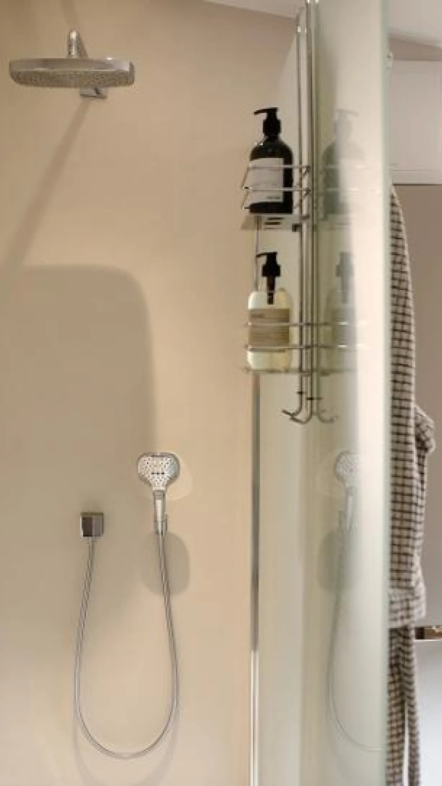 Moderne Dusche im Komplettbad mit Regendusche, Handbrause und Ablagekorb für Duschgel und Shampoo.