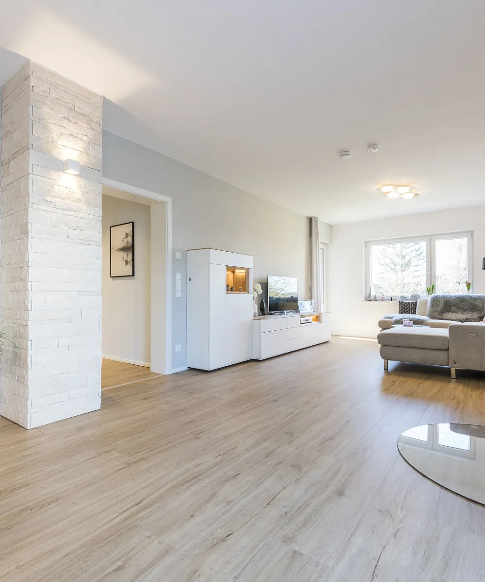 Helles, großes Wohnzimmer mit Kamin und Holzboden.