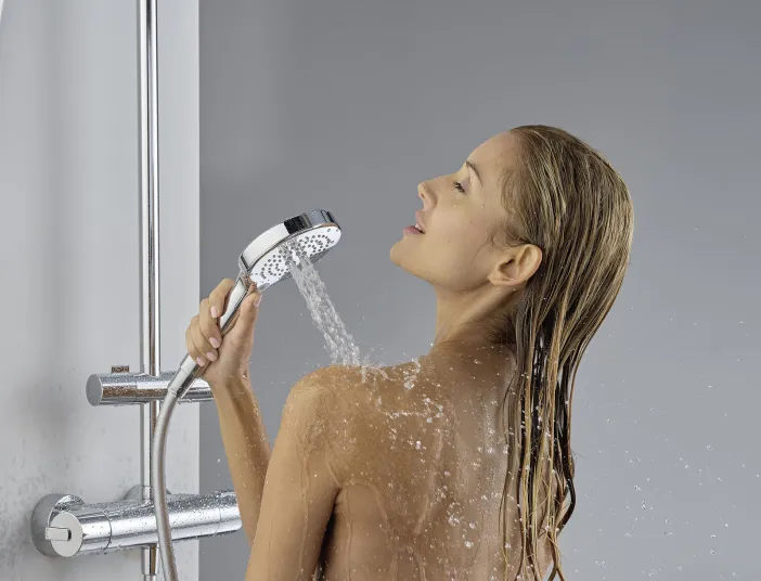 Frau genießt Massage-Strahl der Handbrause. 
