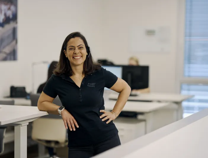 Fröhlich lächelnde Mitarbeiterin eines bad & heizung Handwerksbetriebs in einem modernen, hellen und freundlichen Büro.