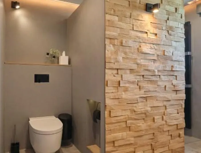 Modernes WC in einem Kompaktbad, mit halbhoher Trennwand in Spaltholz-Optik und dezenter indirekter Beleuchtung.