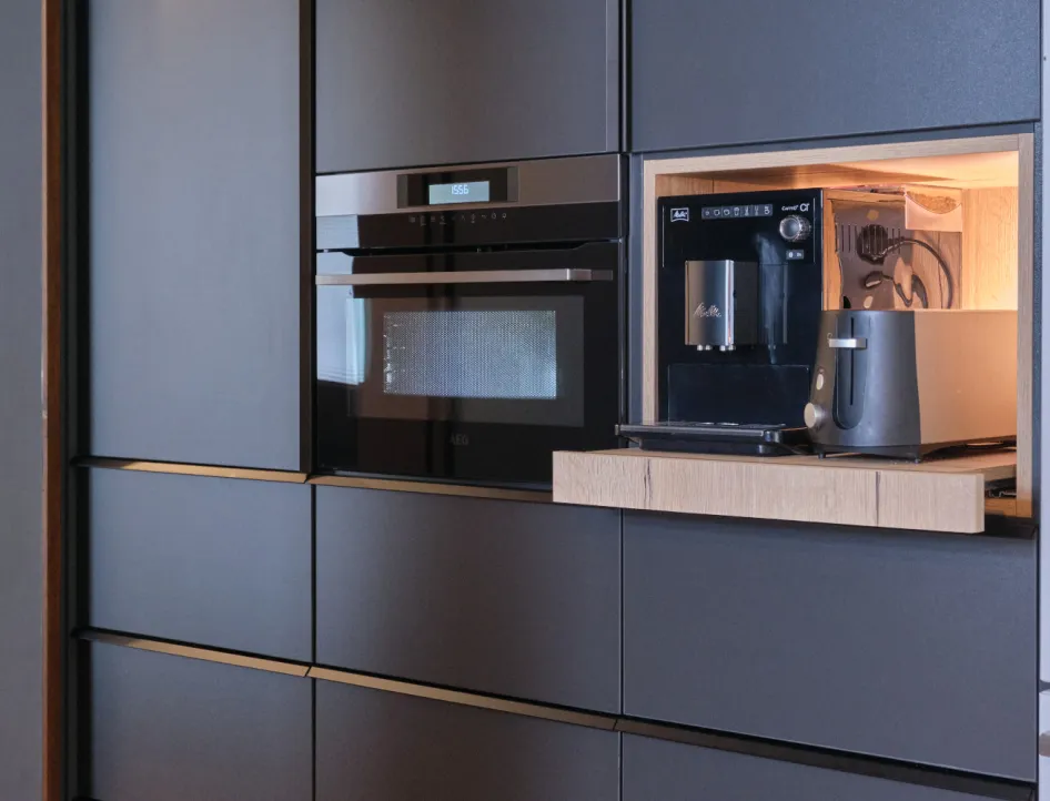 Einbauküche mit schwarzem Backofen, integriertem Kaffeevollautomaten und Toaster in moderner Nische