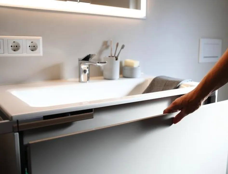 Detailaufnahme eines modernen Waschtischs im Komplettbad mit geöffneter Schublade und Armatur.